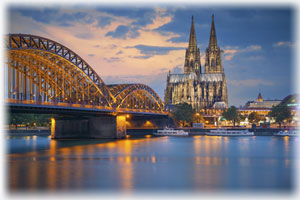 Der Kölner Dom sowie eine Brücke in der Abenddämmerung.