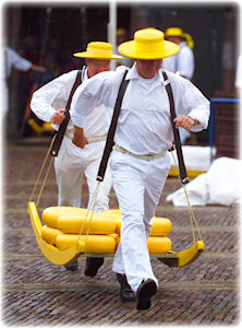 Zwei traditionell gekleidete Männer transportieren große Käselaiber auf den Markt.