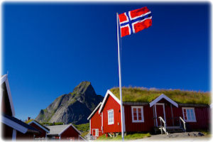 Eine rote Hütte mit Grasdach und einer Flagge von Norwegen im Vordergrund.