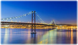 Eine große und beleuchtete Brücke in Portugal bei Nacht.