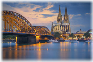 Blick auf den Kölner Dom - eines der größten Kirchengebäude Europas. Der Kölner Dom sowie eine Brücke in der Abenddämmerung.