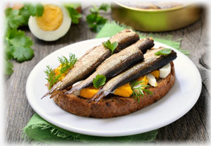 Hier ist ein bekanntes Nationalgericht von Estland zu sehen. Brot mit Fisch. Geräucherte Fische mit Salat auf einem Baguette.