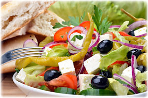 Ein hübsch angerichteter Bauernsalat mit Feta und Fladenbrot.