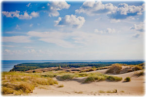 Die Küste Litauens ist definitiv einen Besuch wert. Küstenabschnitt Litauens bei blauem Himmel und Sonnenschein.