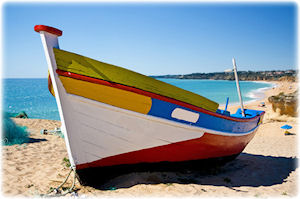 So sehen die traditionellen Fischerboote Portugals aus. Ein bunt bemaltes Fischerboot am Strand von Portugal.